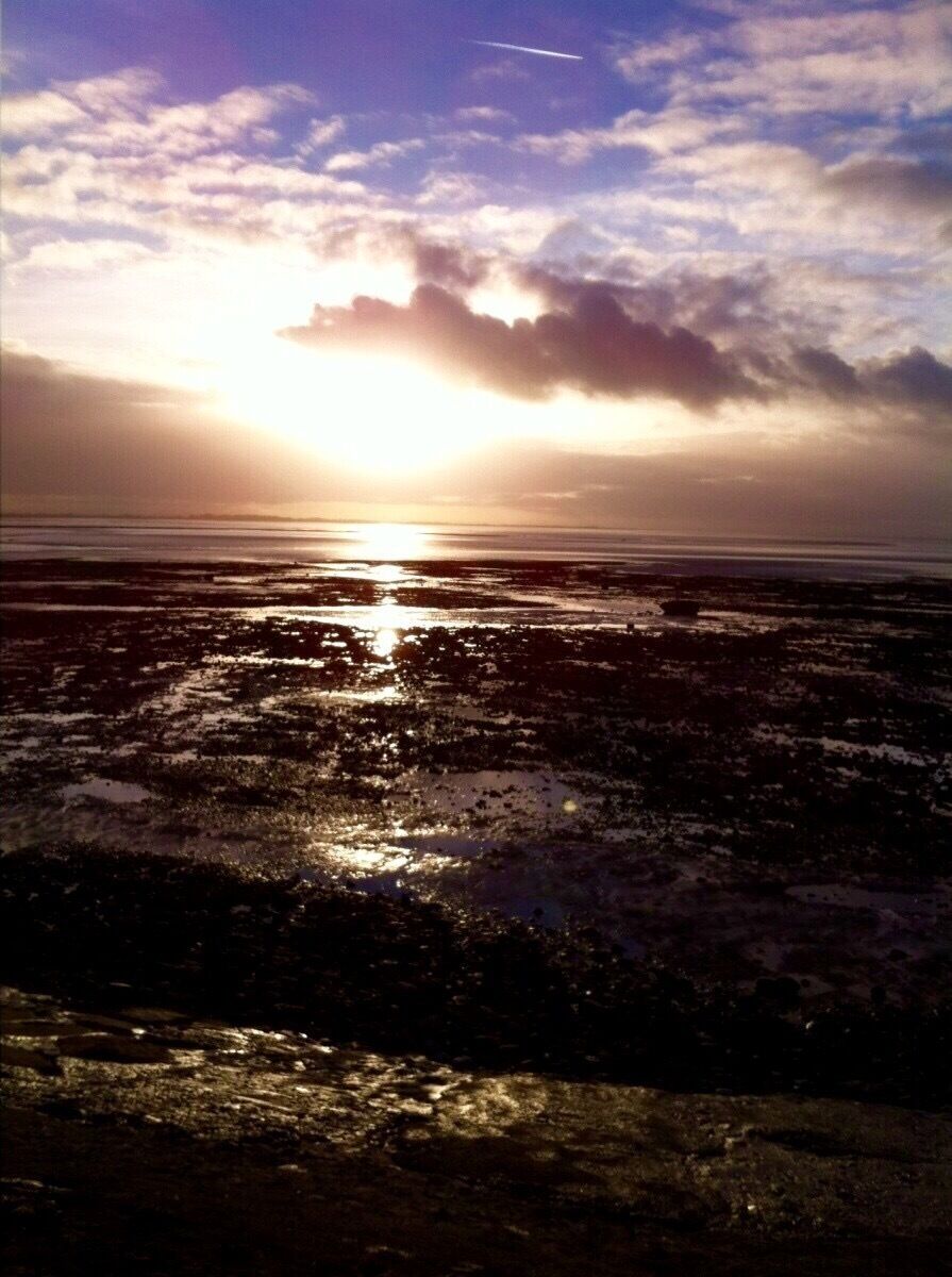 A sunset over a wet landscape with reflections on the water.