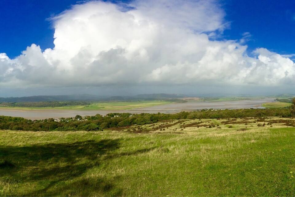 A river valley with a bridge, rolling hills, and scattered trees.