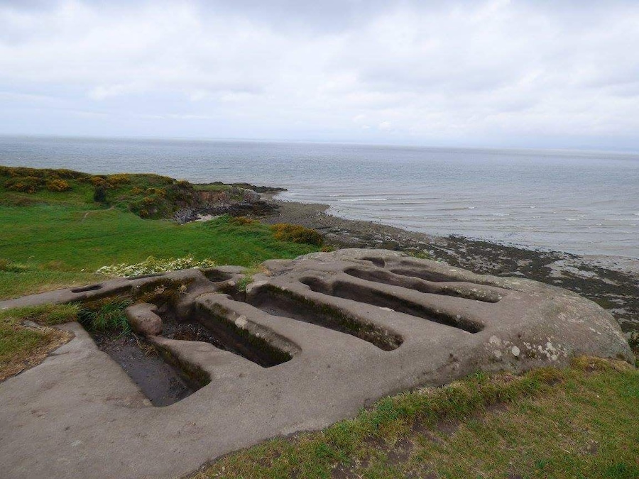 A coastal landscape with a large stone structure near the shore.