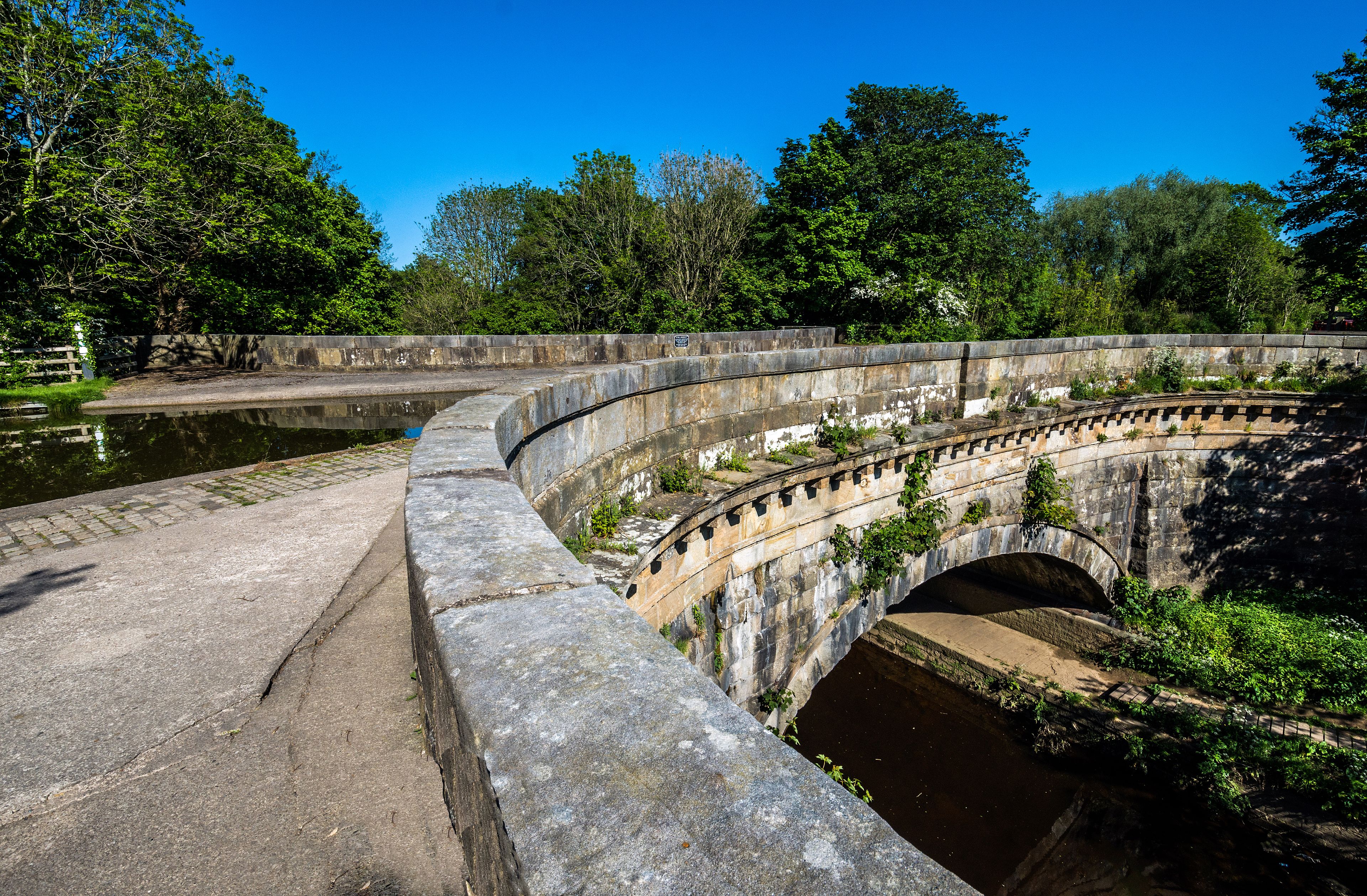 A stone bridge over a canal with surrounding greenery.