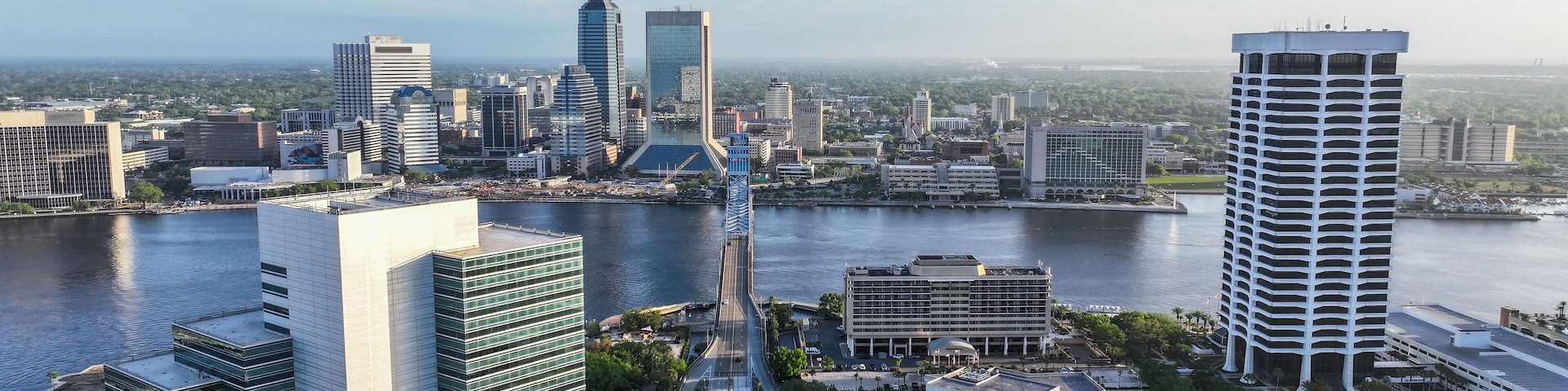 Un paisaje urbano con un río, edificios modernos y un puente.