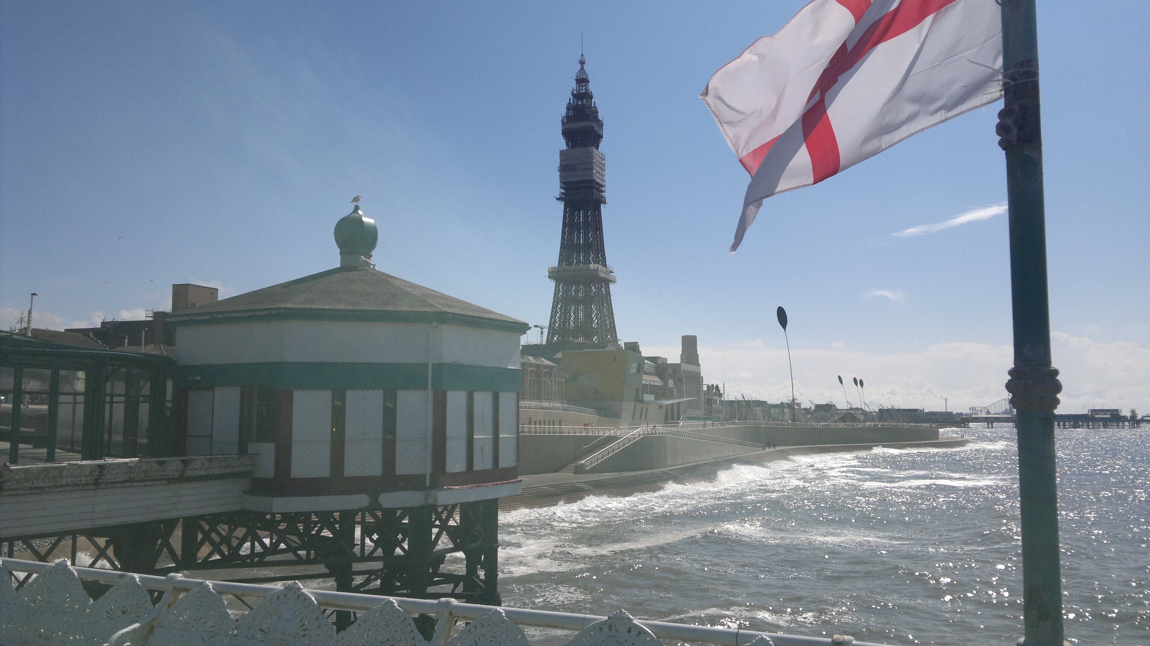 A pier with a small pavilion, a tall tower, and a flag waving in the wind.