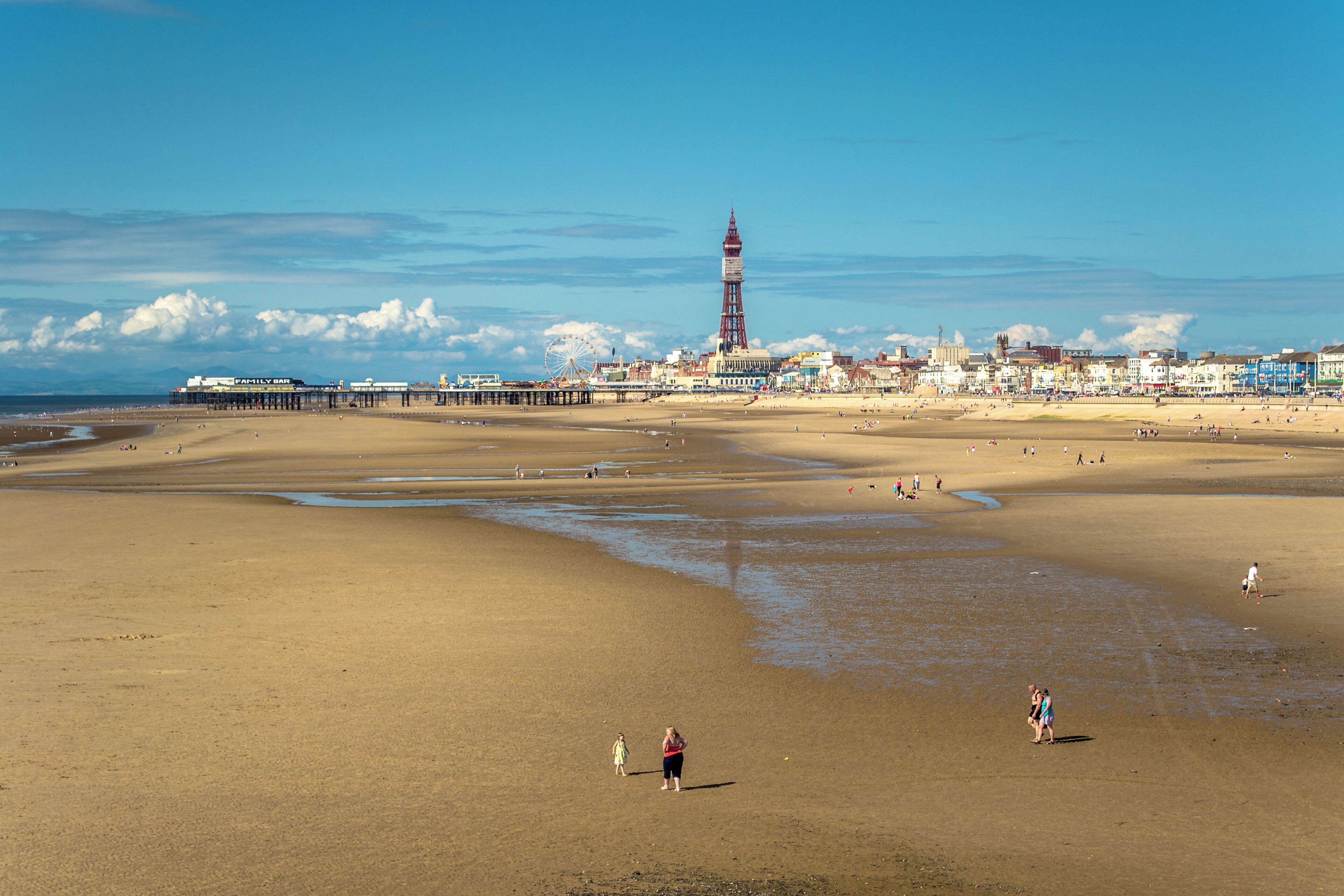 Une plage avec une jetée et un phare en arrière-plan.