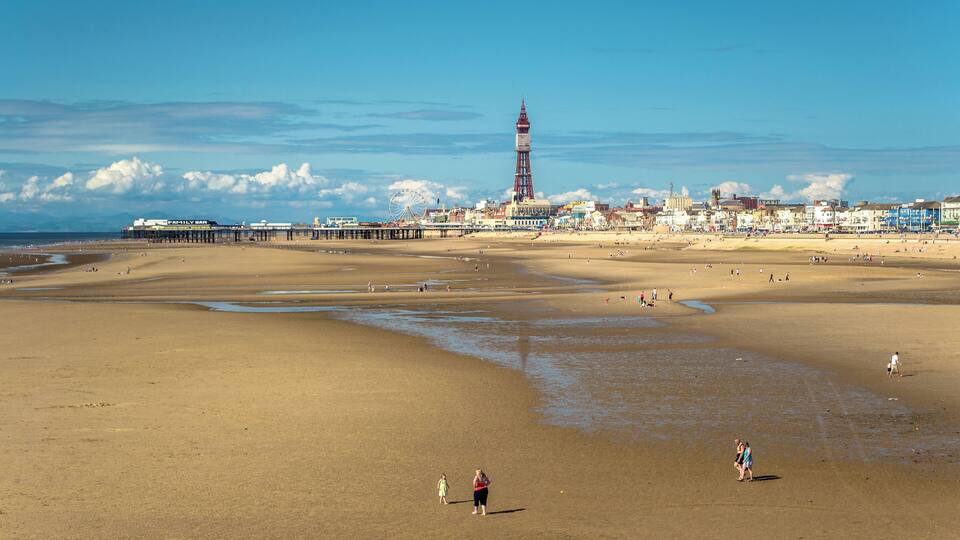 Une plage avec une jetée et un phare en arrière-plan.