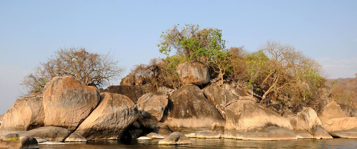 A rocky shoreline with large boulders and sparse vegetation.