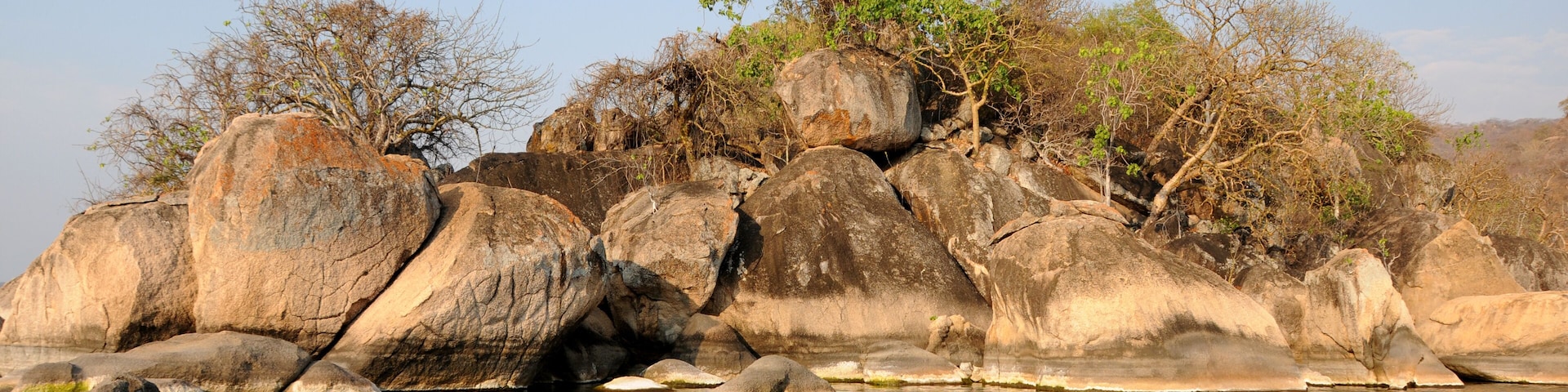 A rocky shoreline with large boulders and sparse vegetation.