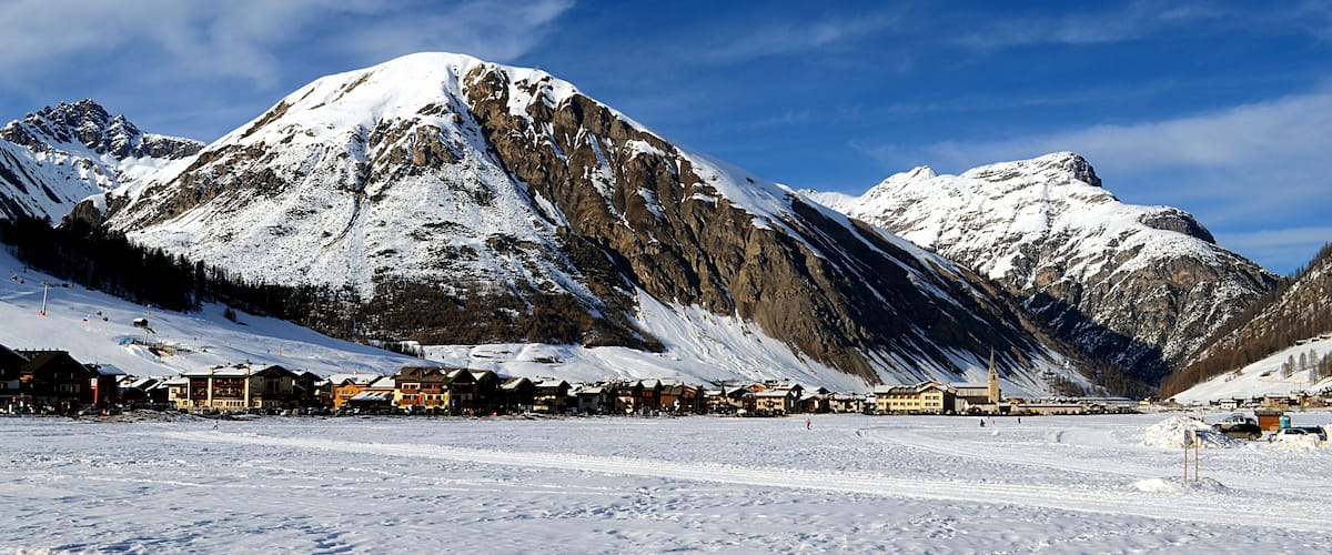A snow-covered mountain range with a ski resort in the foreground.