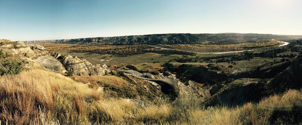 A river valley with a winding road, rocky terrain, and sparse vegetation.