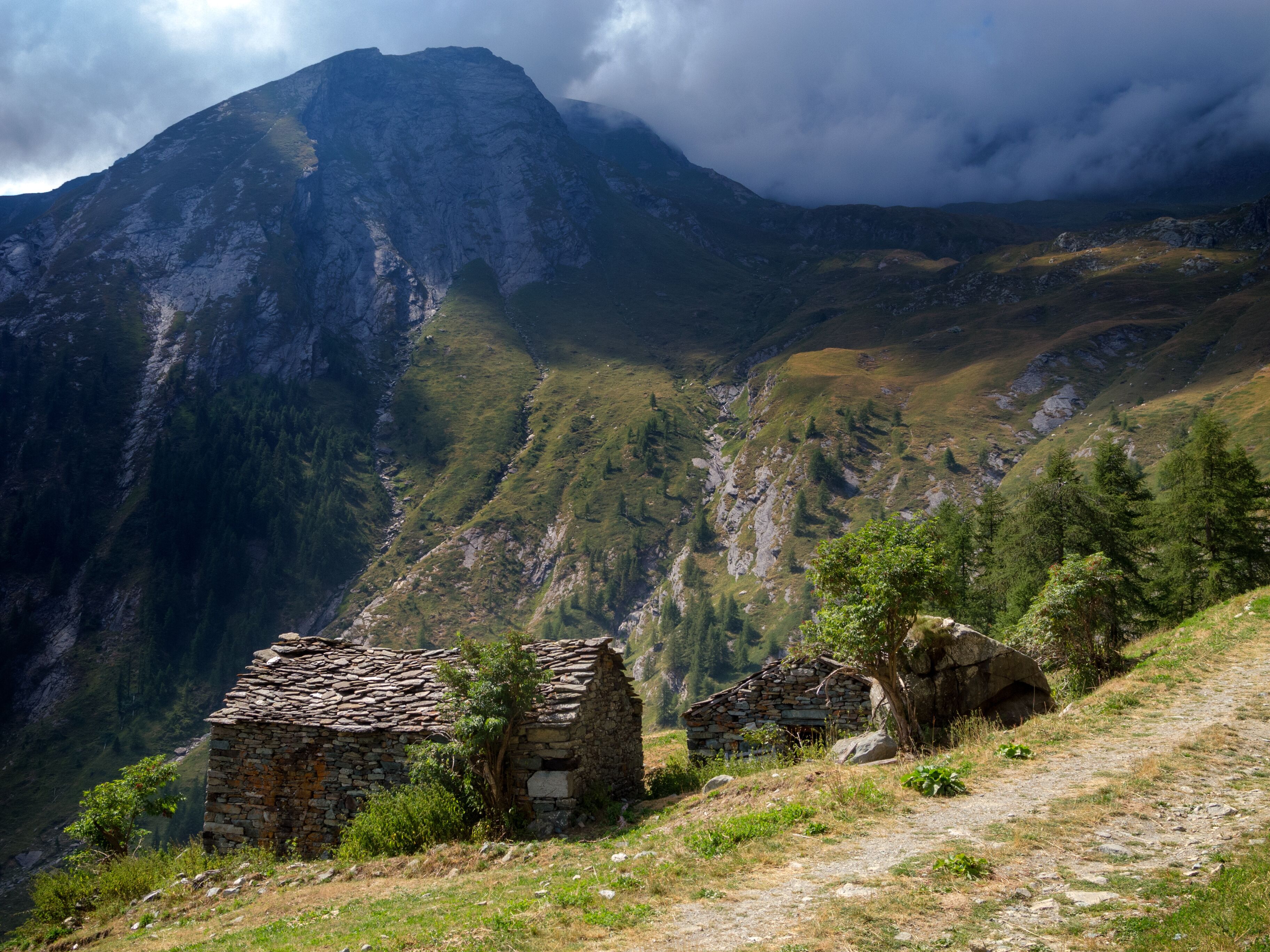 A mountainous landscape with two stone buildings and a path.