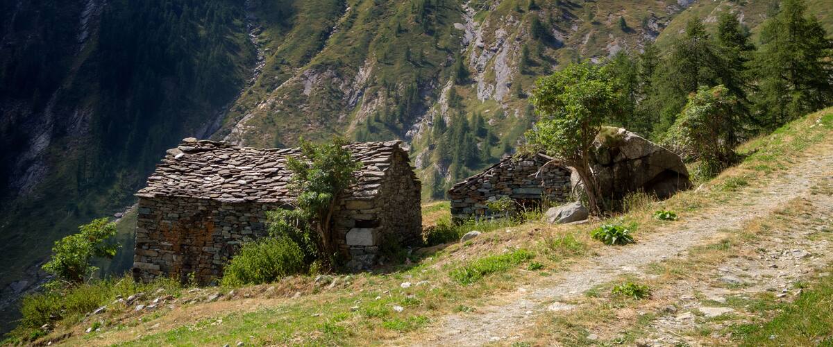 A mountainous landscape with two stone buildings and a path.