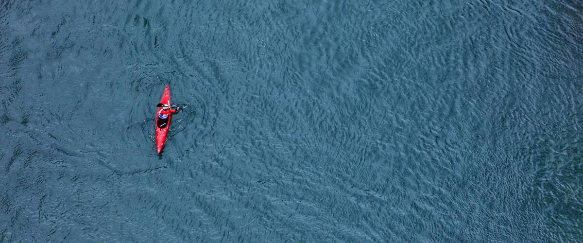 A person in a red kayak on a large body of water.