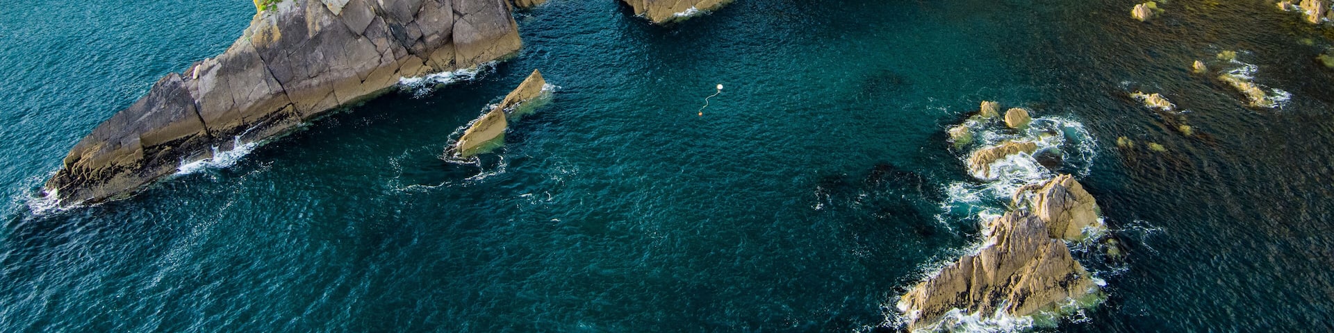 Dunquin or Dun Chaoin pier, Ireland's Sheep Highway. Aerial view of narrow pathway winding down to the pier, ocean coastline, cliffs. Popular location on Slea Head Drive and Wild Atlantic Way.