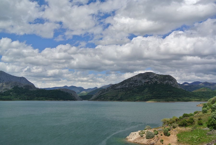 Un lago rodeado de montañas bajo un cielo parcialmente nublado.