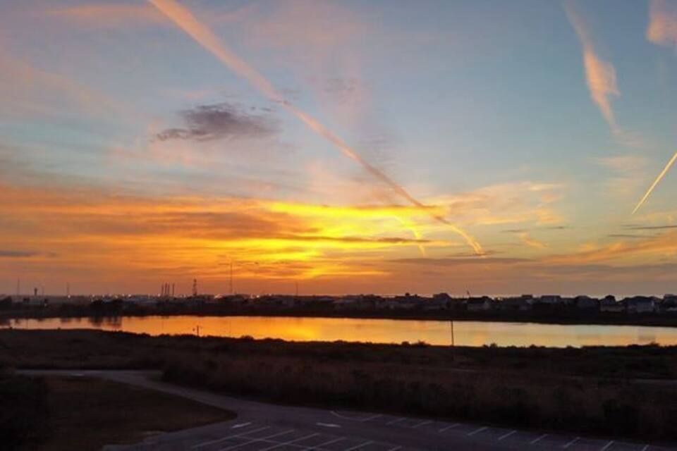 Een zonsondergang boven een wateroppervlak, met een parkeerplaats op de voorgrond.
