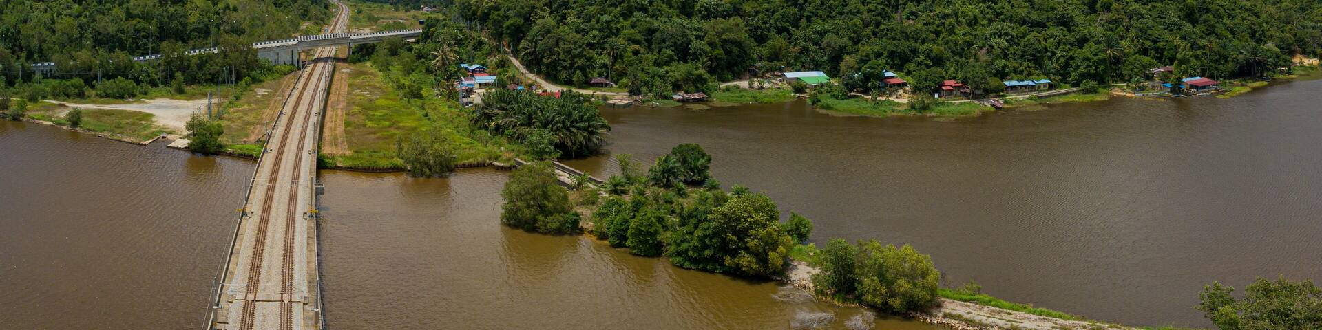 Aerial panoramic drone view of railway track across a lake in Bukit Merah, Simpang Empat Semanggol, Perak, Malaysia.