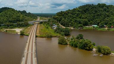Aerial panoramic drone view of railway track across a lake in Bukit Merah, Simpang Empat Semanggol, Perak, Malaysia.