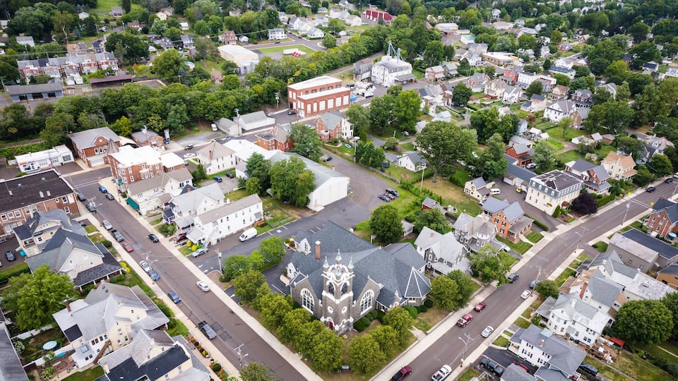 An aerial view of a suburban neighborhood with houses, a church, and a red brick building.