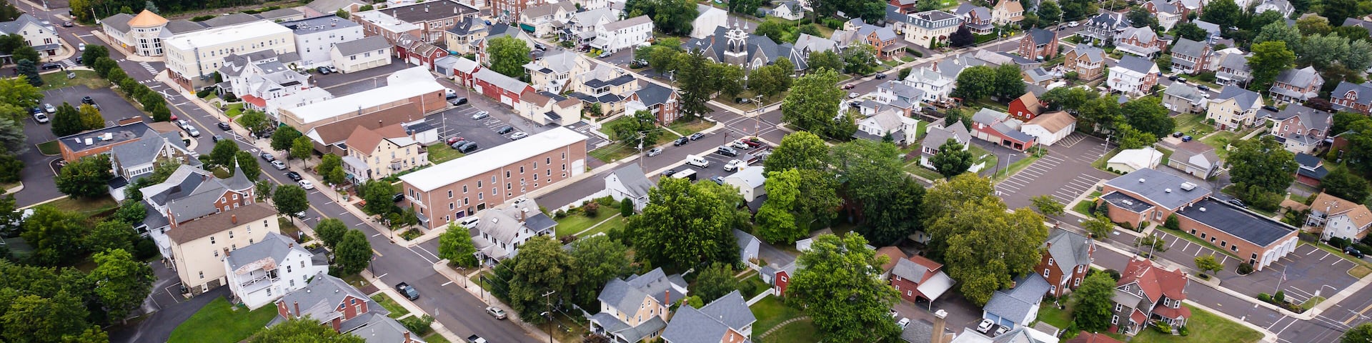An aerial view of a town with a mix of residential houses, commercial buildings, and green spaces.