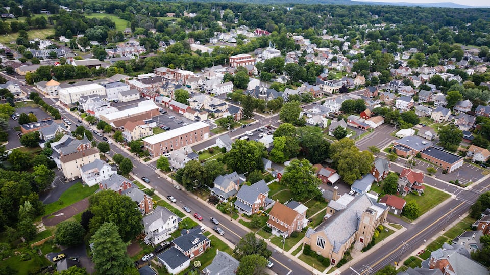 An aerial view of a town with a mix of residential houses, commercial buildings, and green spaces.