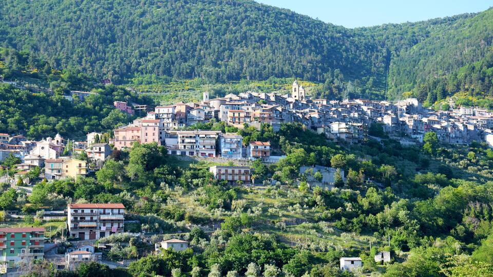 A hillside town with buildings nestled among trees and hills.