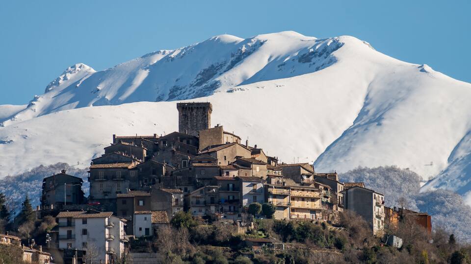 A snow-covered mountain with a historic town nestled at its base.