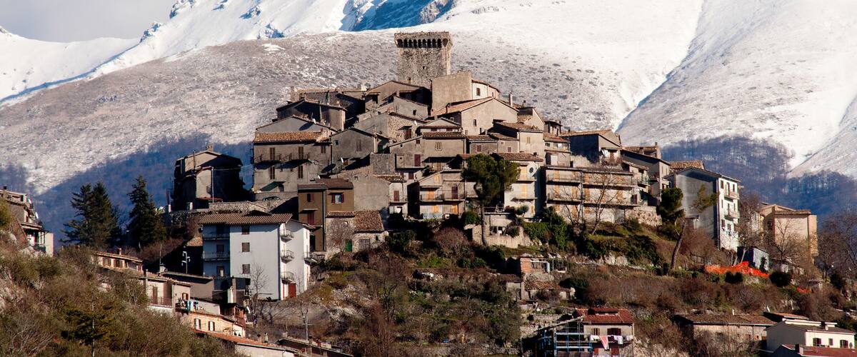 A snow-covered mountain village with historic buildings and a prominent tower.