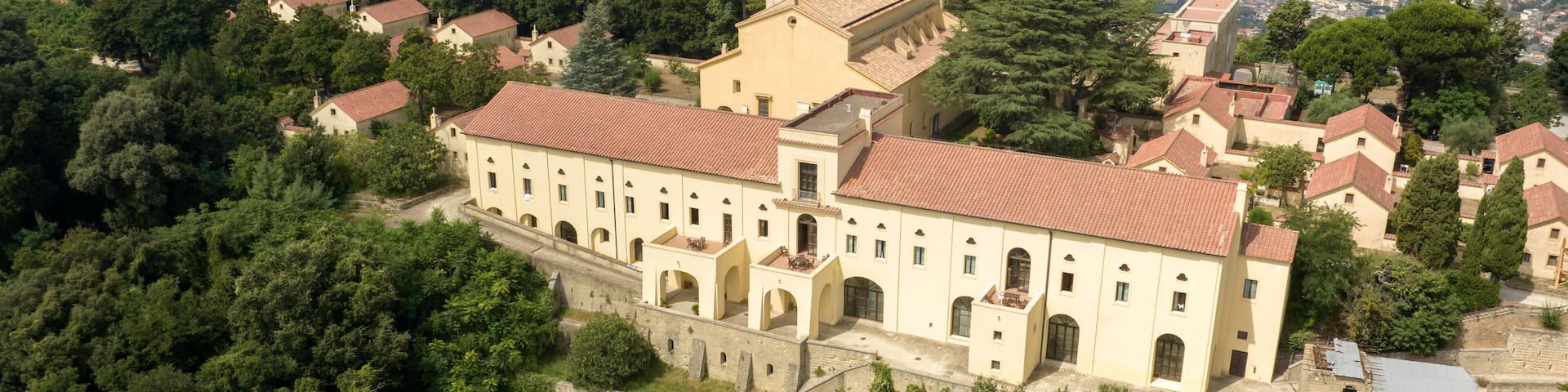 Aerial view of the Eremo dei Camaldoli in Naples, Italy. It's a ancient religious complex with a Catholic church and is located on top of a mountain. The hermitage overlooks the city in the background