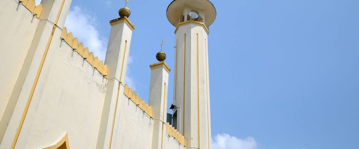 A mosque with three minarets and a dome against a clear blue sky.