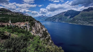 A coastal town with a church on a cliff overlooking a deep blue lake surrounded by mountains.