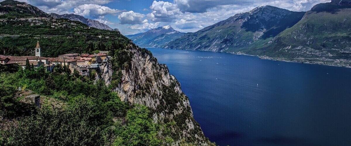 A coastal town with a church on a cliff overlooking a deep blue lake surrounded by mountains.