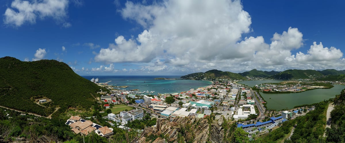 A coastal town with a harbor, surrounded by hills and mountains.