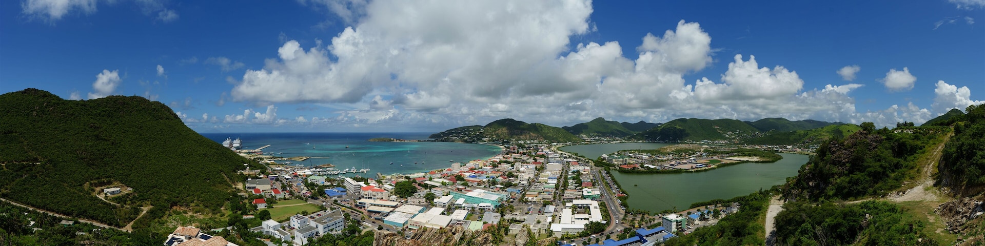 A coastal town with a harbor, surrounded by hills and mountains.
