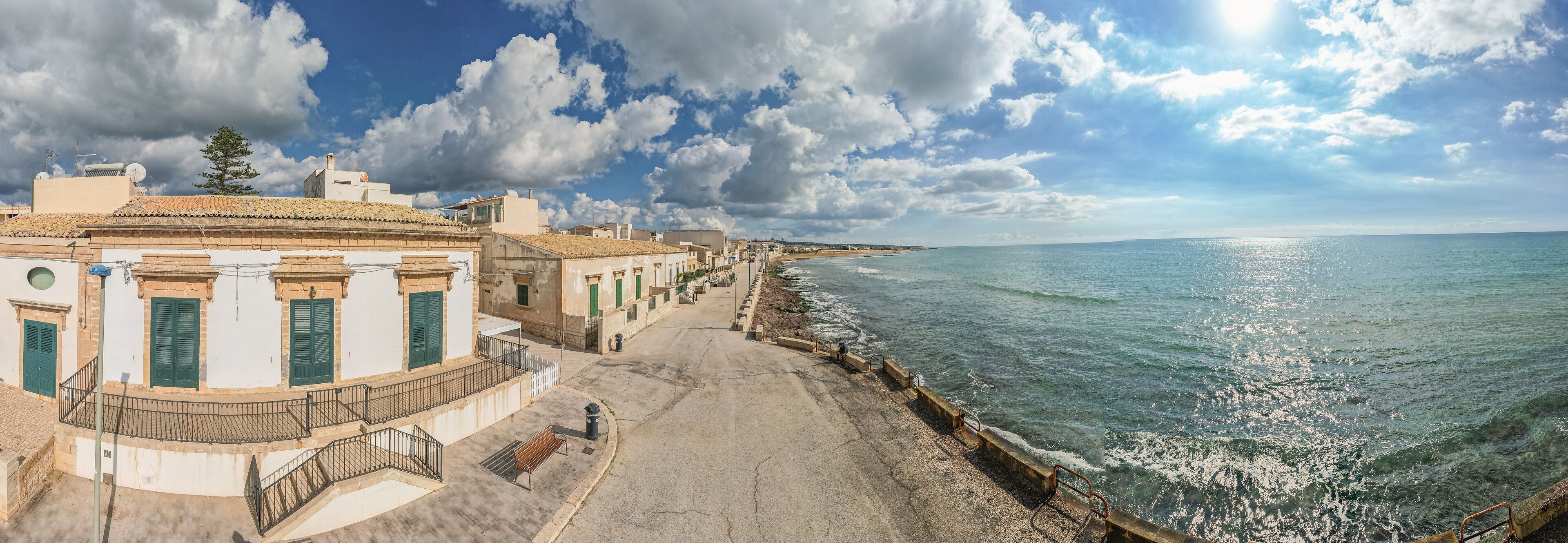 A coastal town with white buildings, a promenade, and the sea.
