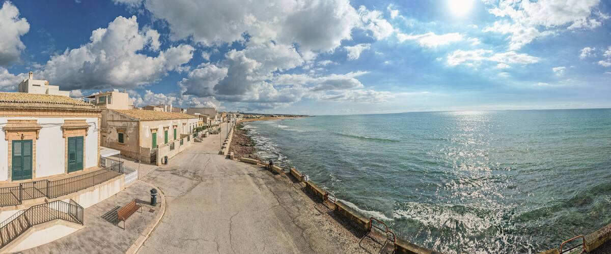 A coastal town with white buildings, a promenade, and the sea.