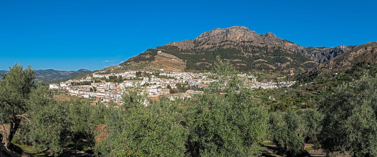 A town nestled in a valley with a prominent mountain in the background.