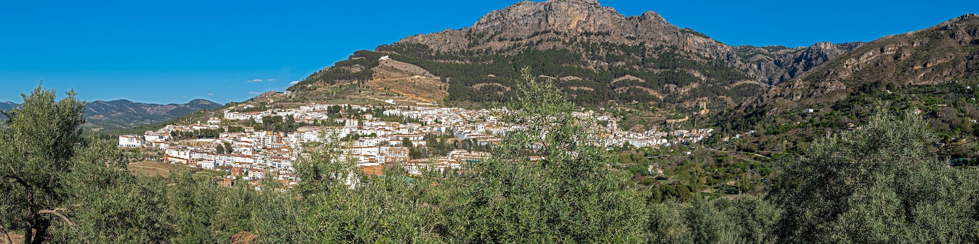 A town nestled in a valley with a prominent mountain in the background.