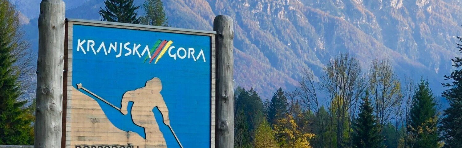 A sign welcoming visitors to Kranska Gora, featuring a skier silhouette and mentions the POKAL VITRANG EJS SKI WORLD CUP and FIS WORLD CUP SKI JUMPING.