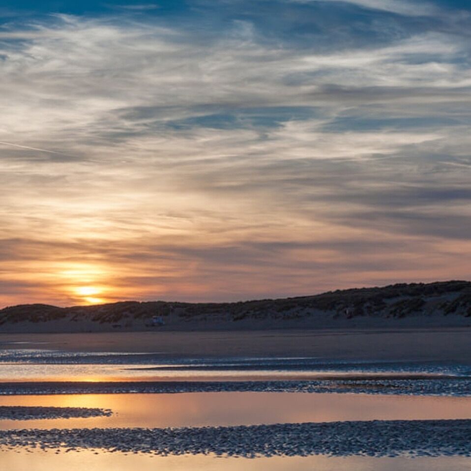 A sunset over a calm lake with a distant shoreline.
