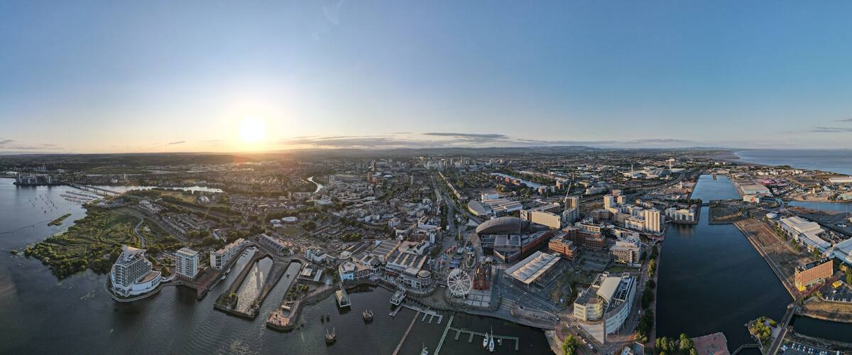 Aerial panorama of Cardiff city at sunset with Cardiff Bay in the foreground including a big ferris wheel and fair and the cityscape in the background, Cardiff Bay, UK