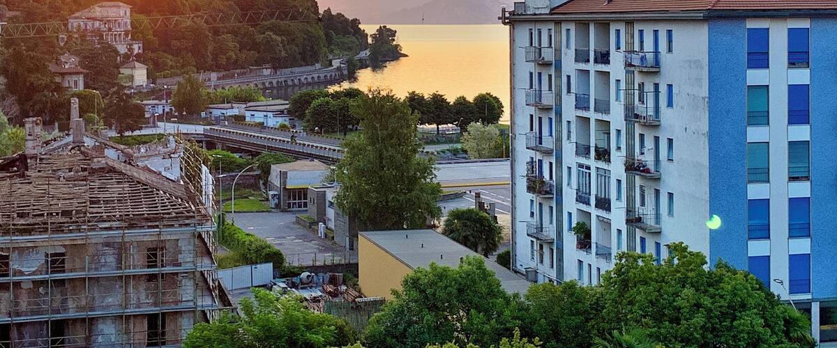 A sunset over a lake with buildings and mountains in the background.