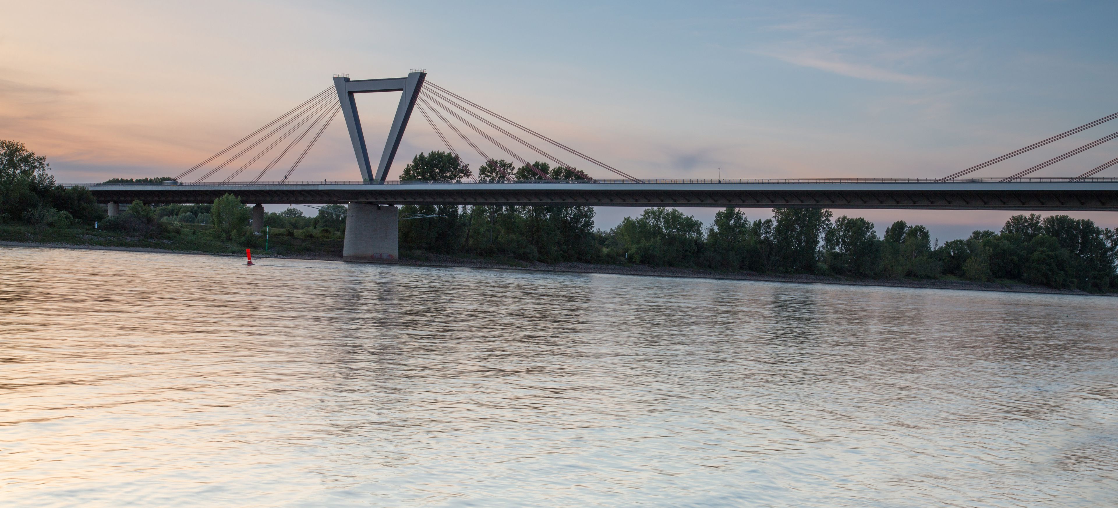 A bridge over a river with trees on the banks.