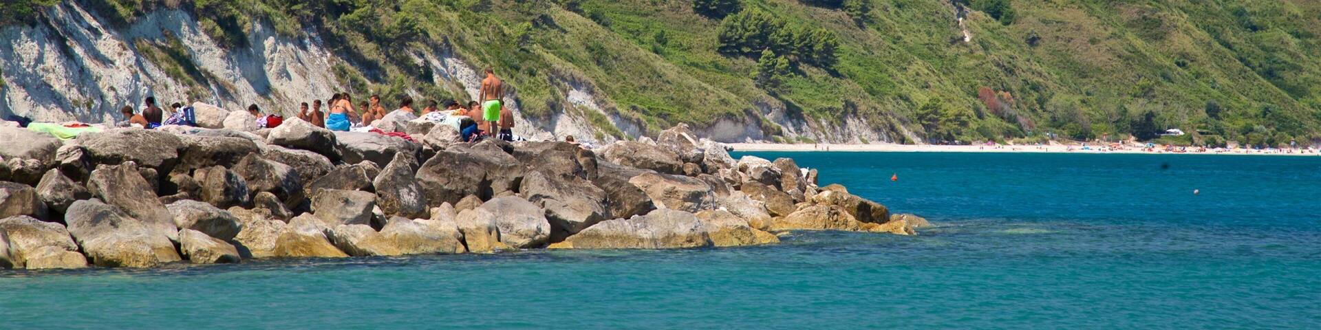 Portonovo which includes a pebble beach and general coastal views as well as a small group of people