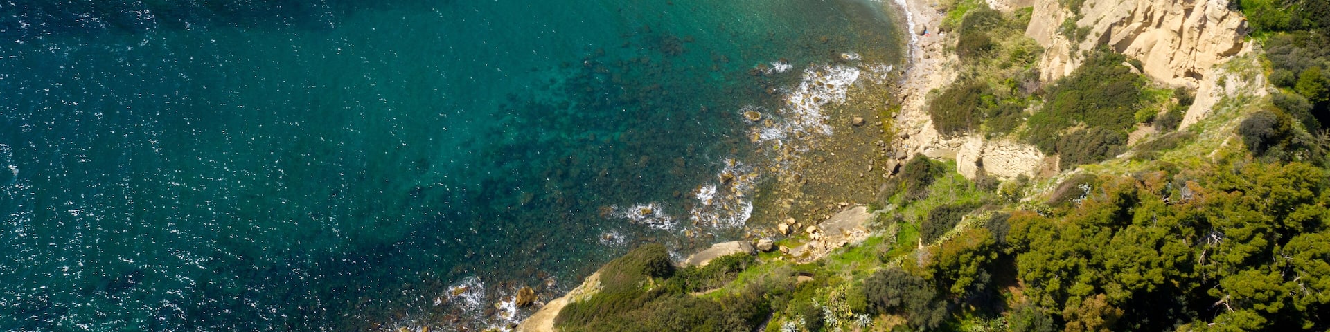 Aerial view on the Trentaremi bay of Posillipo, a district of Naples, Italy. There is a small empty beach in a cove. The coast overlooks the Mediterranean Sea.