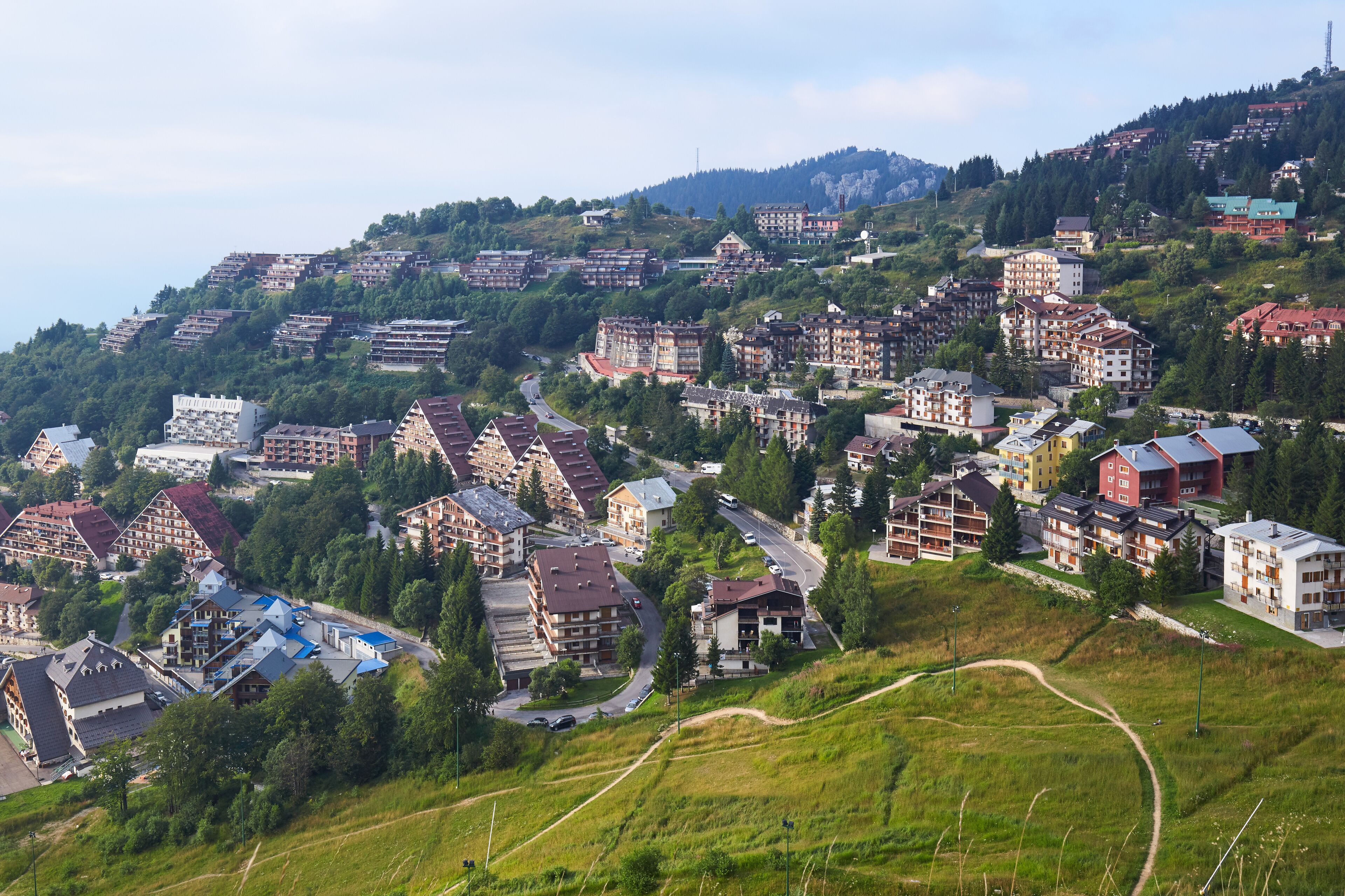 A hillside town with buildings, roads, and greenery.
