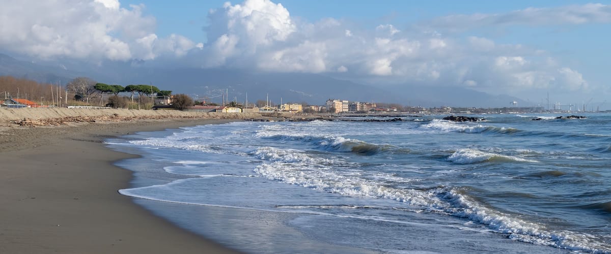 Sandy beach with breaking waves. Marinella di Sarzana looking towards Marina di Carrara. Mediterranean Sea, Europe. Winter season.