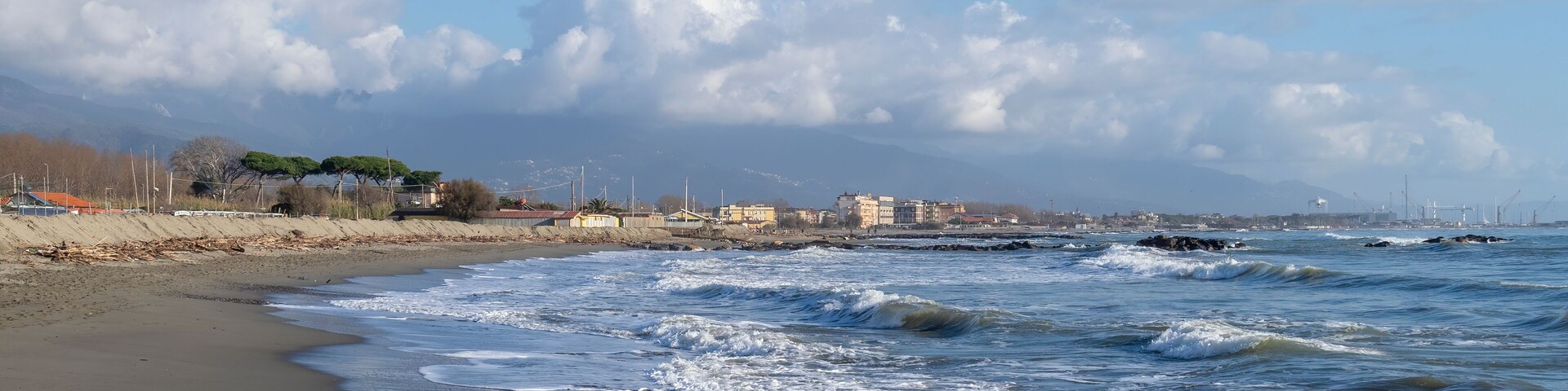 Sandy beach with breaking waves. Marinella di Sarzana looking towards Marina di Carrara. Mediterranean Sea, Europe. Winter season.