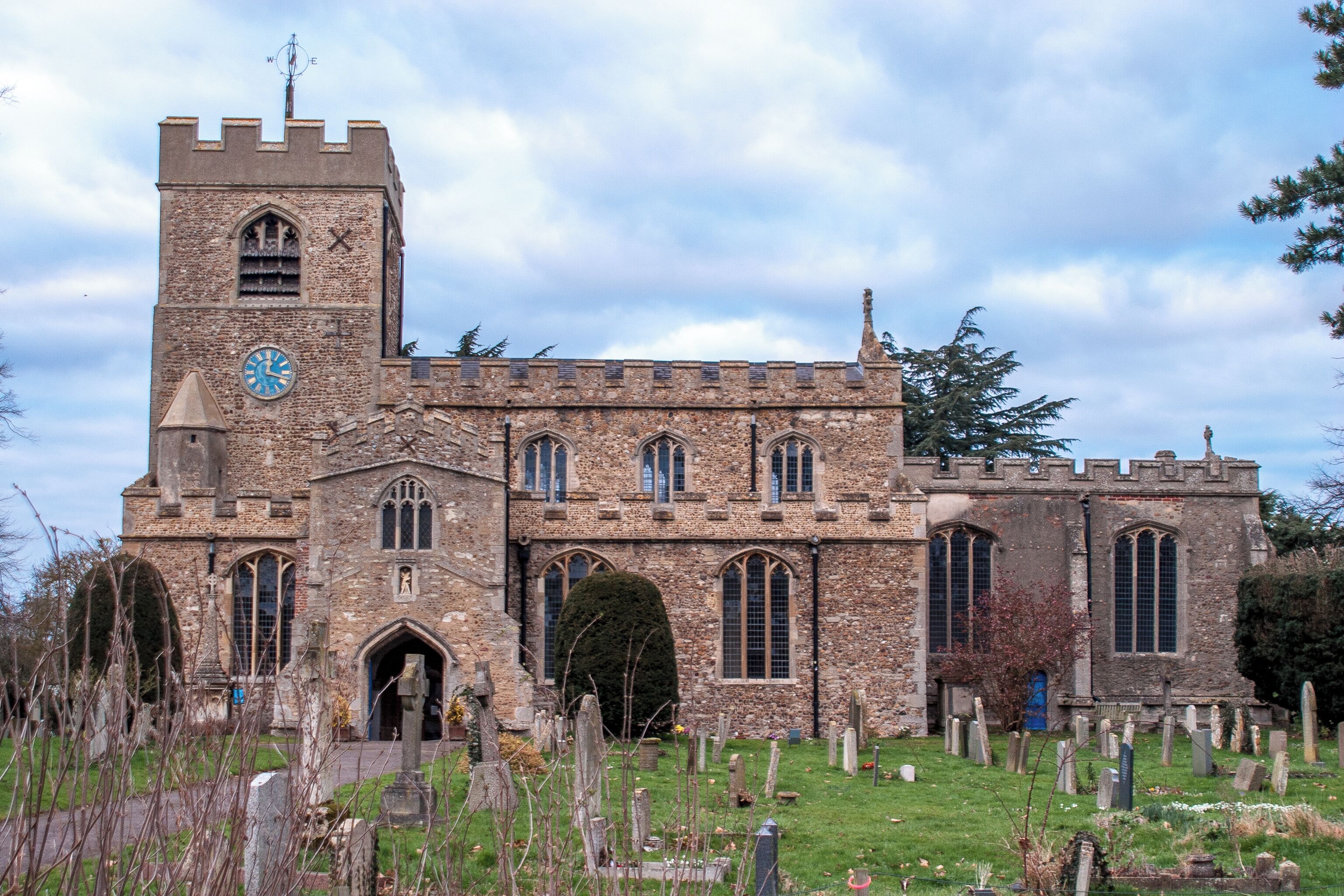 A historic church with a clock tower and a cemetery in front.
