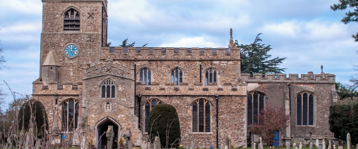 A historic church with a clock tower and a cemetery in front.