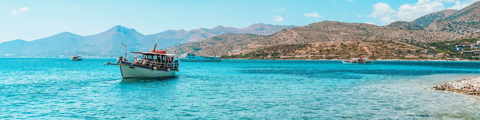 Gulf of Elounda. Pleasure boat in the bay against a mountains ridge and blue cloudless sky. The view of the pleasure boat in Elounda bay from the Spinalonga island