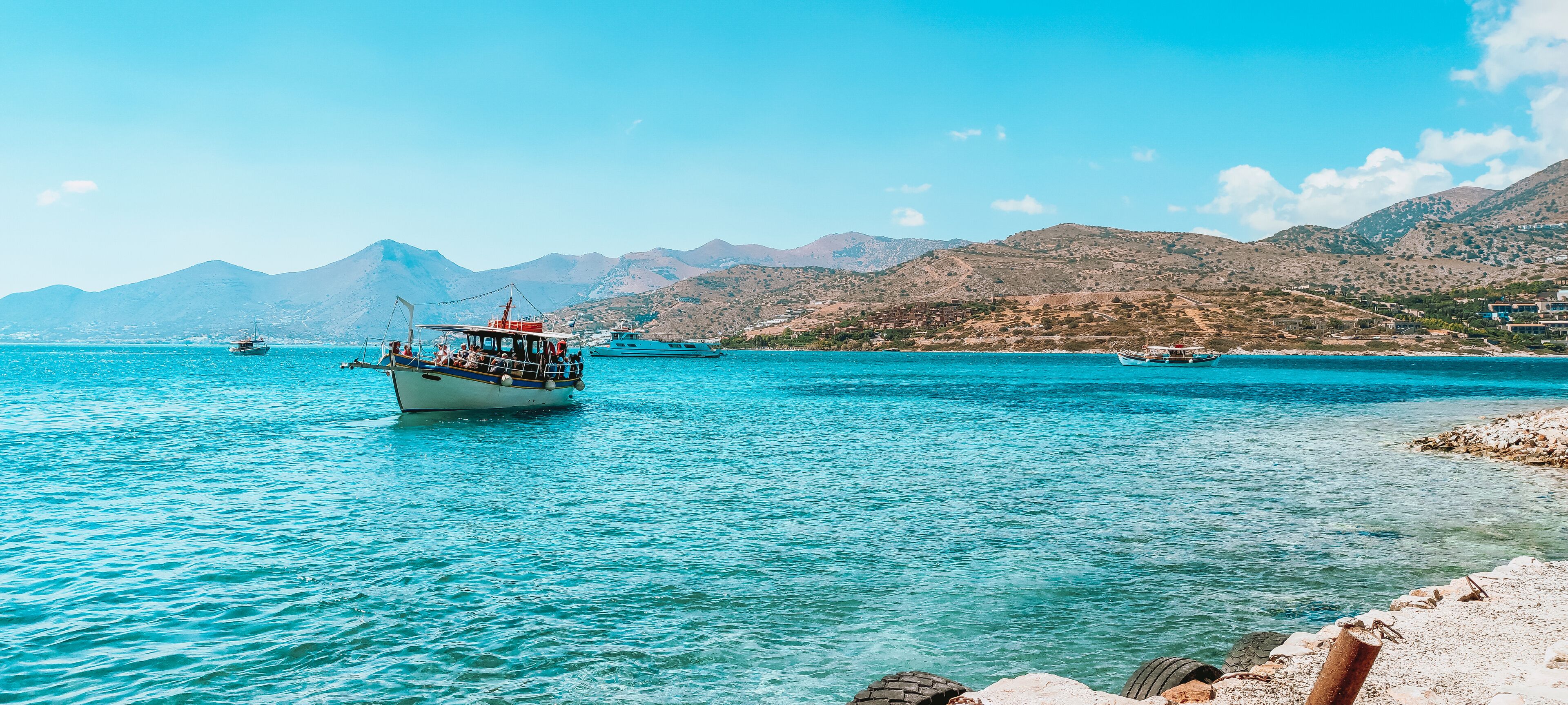 A boat on a turquoise sea with mountains in the background.